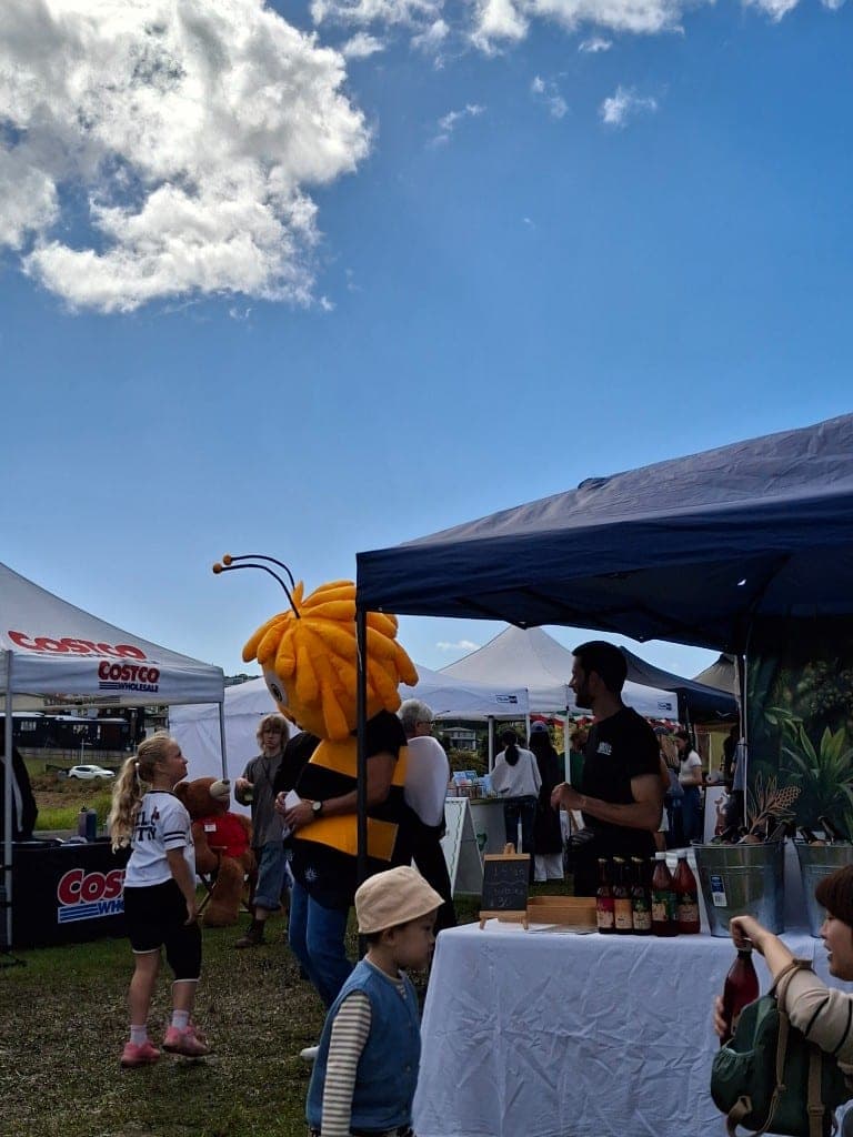 The Aroā bee mascot in profile, sipping a bottle of Jun